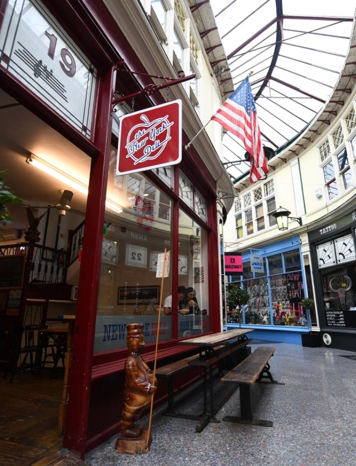 A curved shopping arcade with independent shops and a glass roof.