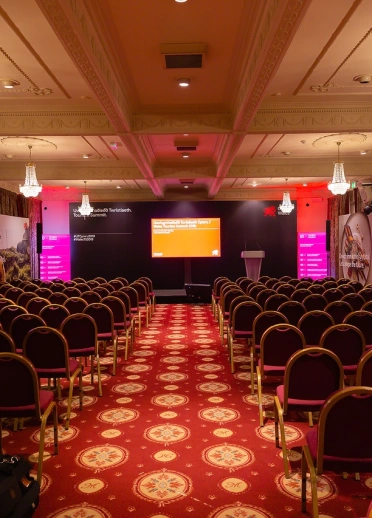 A conference room with chairs set out in a cinema style looking at a large display screen.