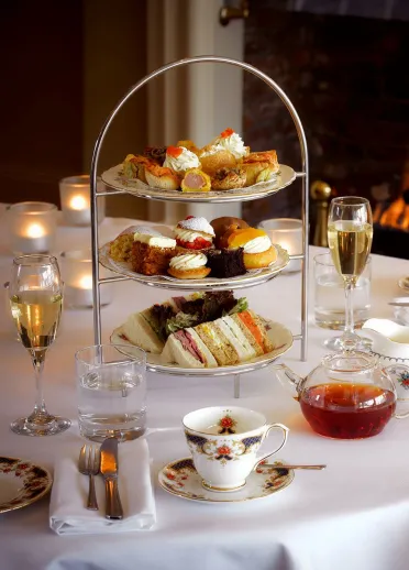 Afternoon tea set up on a table with a roaring fire in the background.