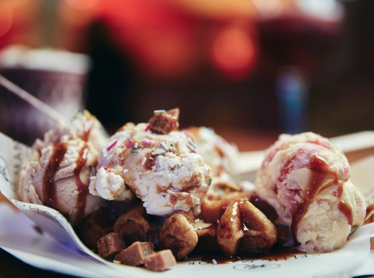 A bowl of icec cream with sauce and garnish.