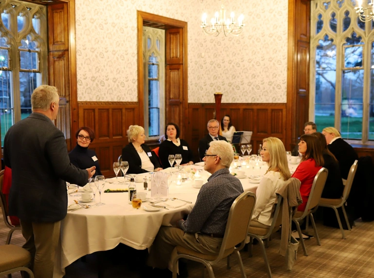 People sitting around a dining table in a grand castle.