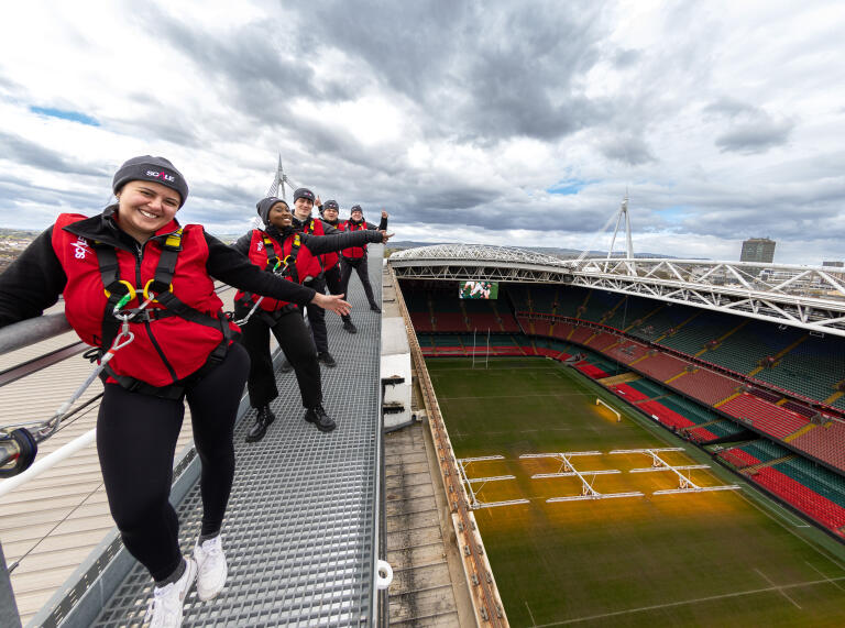 People at the top of teh Principality stadium in safety gear with pitch views below 