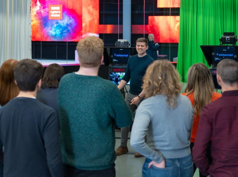 people listening to a BCC Cymru Wales representative on a tour of the studio 