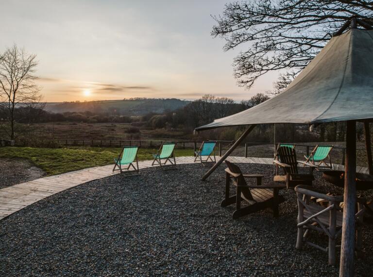 Outdoor tipi with chairs overlooking the mountains of Cardigan and sun setting 