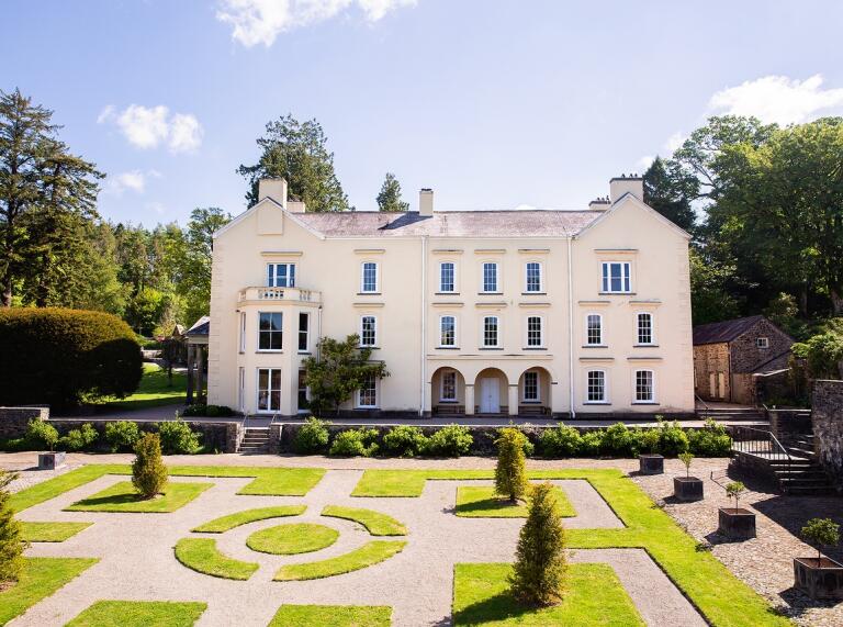 white building with manicured lawns and trees in the forefront