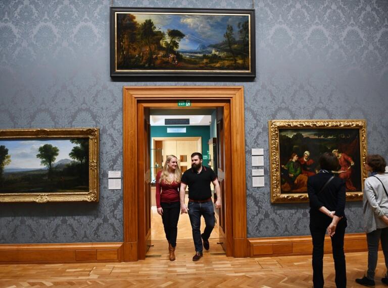 people walking through teh national museum Cardiff looking at art on the walls 