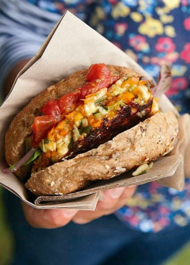 Burgers held in a napkin, filled with bacon, cheese and garnish.