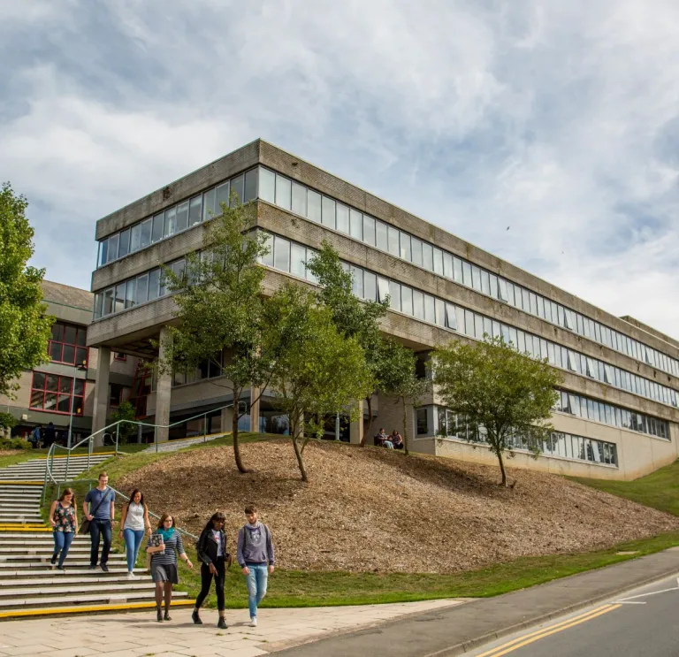 External view of a university building with students walking down the steps.