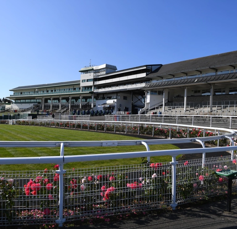 A racecourse surrounded by flowers, a seating area and hospitality boxes.