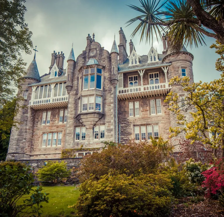 An external view of a grand chateau framed with trees and foliage.