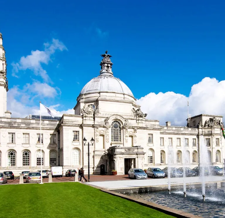 Exterior shot of Cardiff City Hall with clock tower, and fountains.