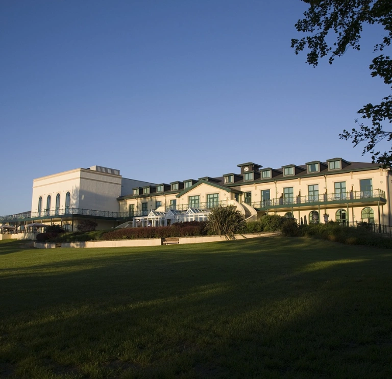 The frontage of a large hotel with lawns in the foreground.