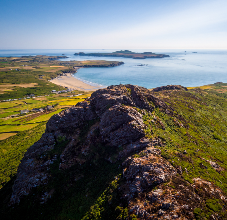 View from a headland of a beach and coastline on a sunny day.