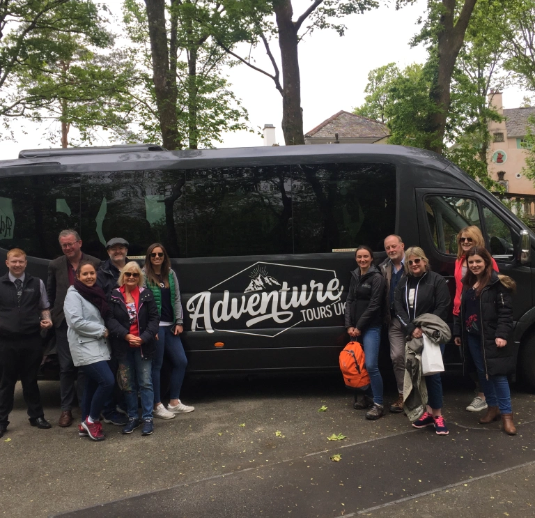 Group of people standing outside mini bus.