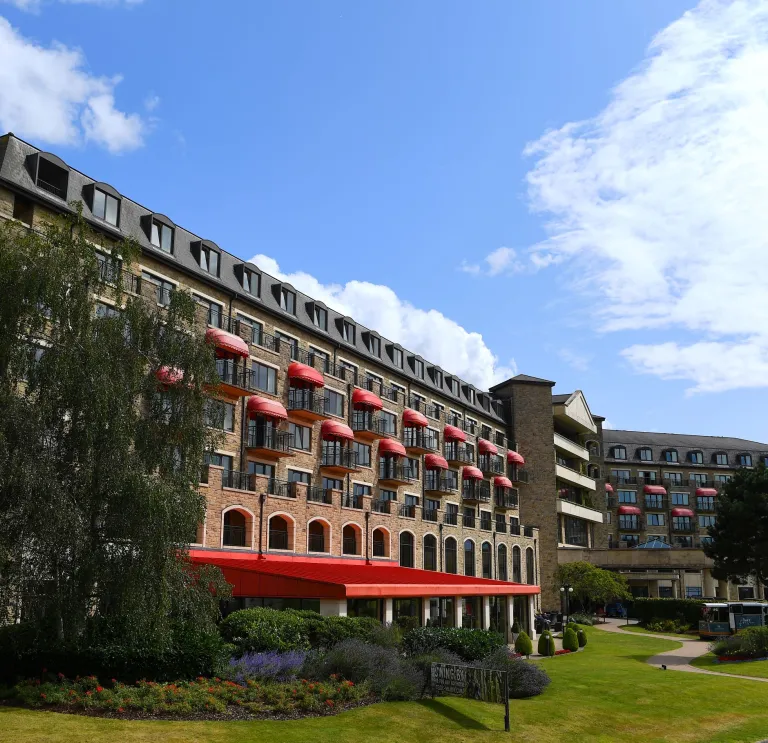 Exterior of hotel with manicured green lawns and trees.