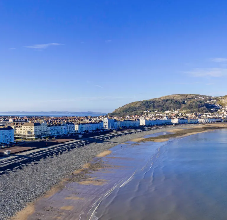 The shoreline of a beach resort lined with hotels with cliff tops beyond.