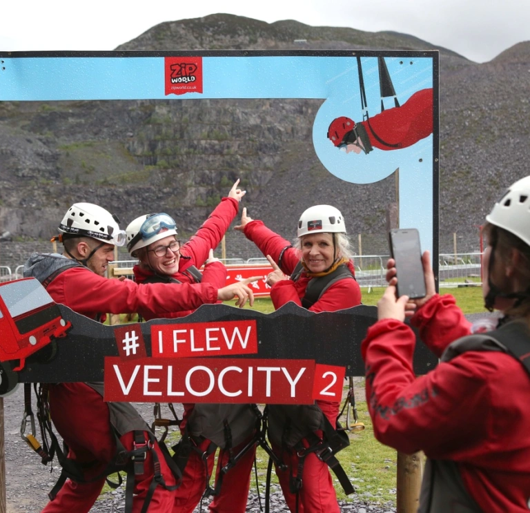 A group posing in a camera frame after travelling down a zip wire.