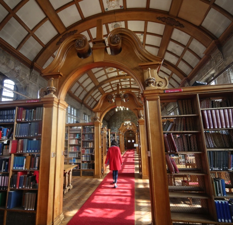 A library with panelled ceiling and books on shelves along the hallway.