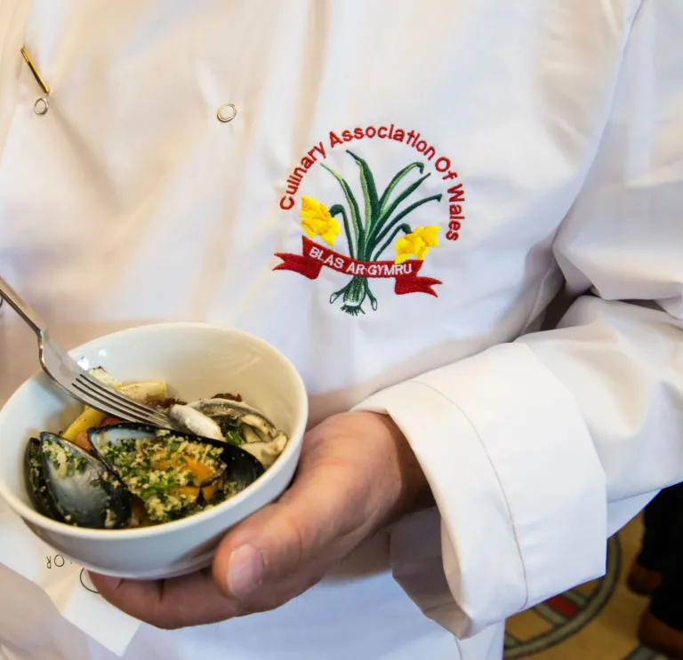 Chef in apron displaying Culinary Association of Wales badge 