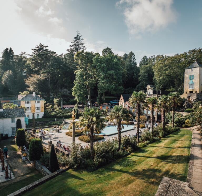 grounds of Portmeirion showing a giant chess board on the grass with green trees behind ss and plants o 