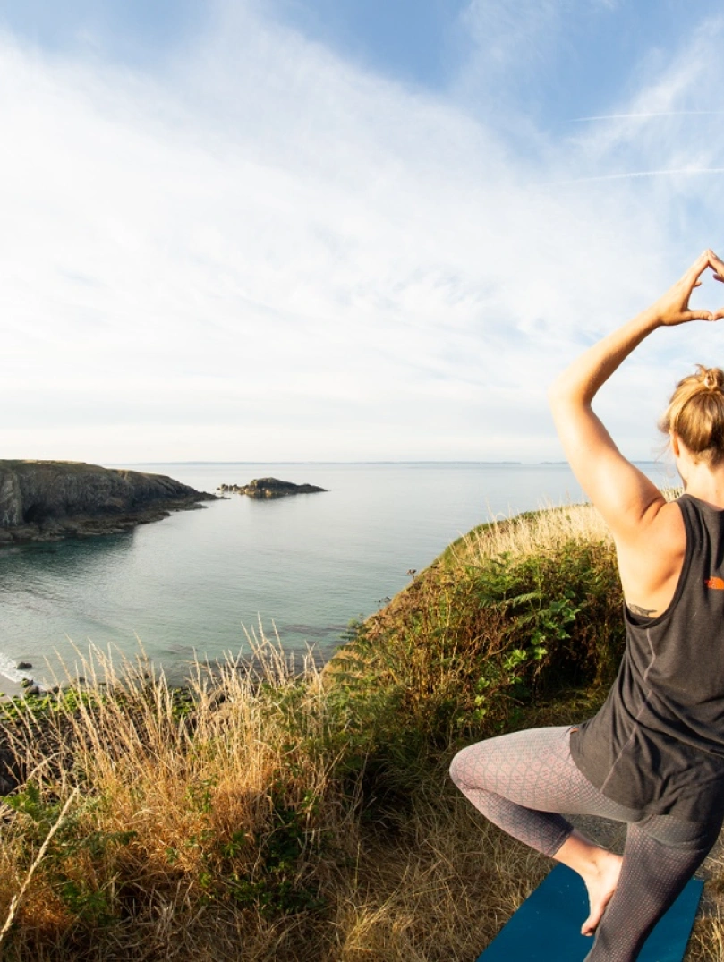 Person doing yoga overlooking beach.
