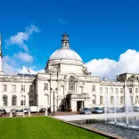 Exterior shot of Cardiff City Hall with clock tower, and fountains.