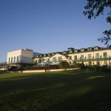 The frontage of a large hotel with lawns in the foreground.