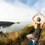 Person doing yoga overlooking beach.