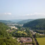 Aerial view of a major road through the valleys with a castle perched on a mountain.